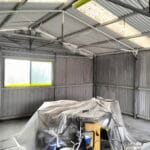Industrial shed interior spraying preparation with spray machine and protective masking by S and R Painting Group in Bayswater.