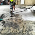 S&R Painting Group professional painter using a heavy-duty floor grinding machine to prepare a concrete surface in Southeast Melbourne garage floor.