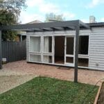 Professionally painted weatherboard backyard studio with dark grey pergola posts and a matching timber boundary fence by S and R Painting Group in Oakleigh and Malvern East.