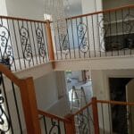 Multi level residential stairwell with freshly painted white walls and ornate wrought iron balustrades by S and R Painting Group in Mount Waverley.