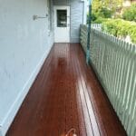 Professionally oiled rich timber deck contrasting with a freshly painted white picket fence by S and R Painting Group in Cranbourne and Clyde.