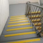 Professionally painted commercial concrete staircase with yellow non-slip safety stair nosing by S and R Painting Group in Springvale and Braeside.
